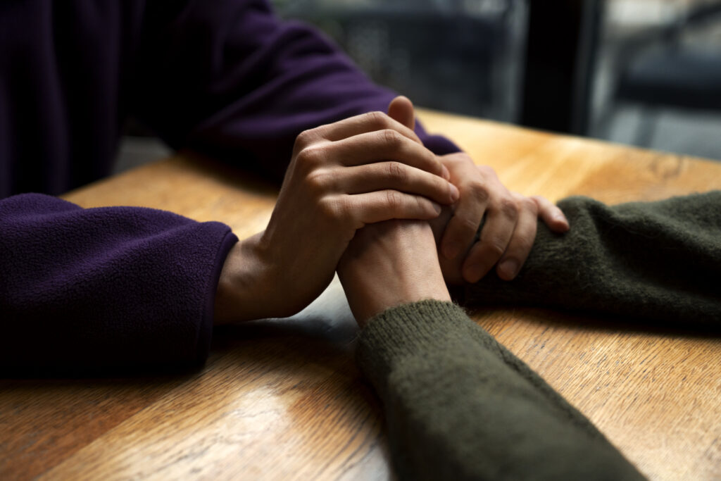 Elderly hands being gently held by a caregiver, symbolising compassion, support, and emotional healing in home care.